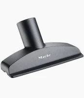 A black Miele upholstery nozzle for vacuums, with a flat rectangular shape and a black attachment at the top.