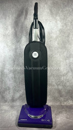 Upright Riccar vacuum cleaner in black color with a purple base, featuring a carrying handle and a power cord.