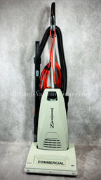 A Titan TC6000 Commercial upright vacuum cleaner in beige color with a metal handle and black accents. The vacuum has a clean air motor, telescopic wand, and on-board tools.